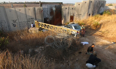 Landscape view of men sitting on ground in front of Israel's West Bank wall