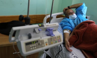 A man hooked up to a medical machine reclines on a hospital bed
