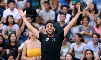 Man stands before crowd with arms wide open 