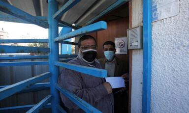 A man stands in a metal swing door carrying a piece of paper