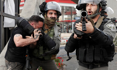 An Israeli police officer puts a Palestinian in a choke hold while another officer points a gun