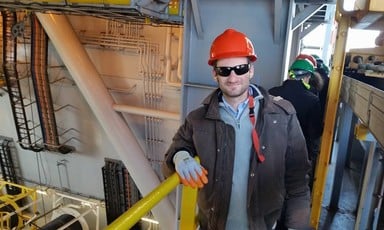 Man surrounded by machinery wears hard hat and sunglasses 
