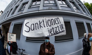A man in face mask holds up a sign in German