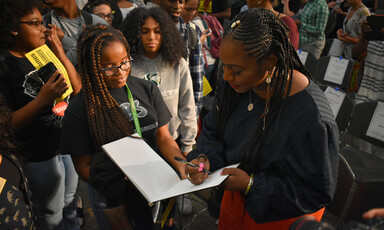 Woman signs book with onlookers