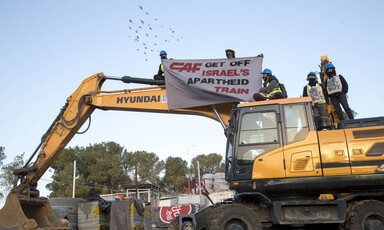 People on top of construction equipment hold banner