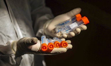 Gloved hands hold medical vials