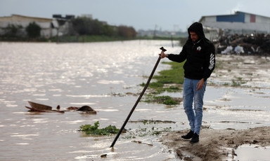 Man stands beside flooded land 