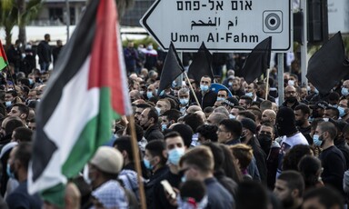 People demonstrate in large numbers, holding flags  