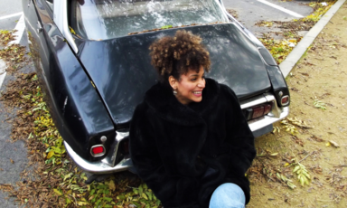 Woman smiles while sitting beside a car