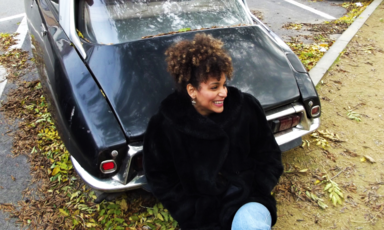 Woman smiles while sitting beside a car 