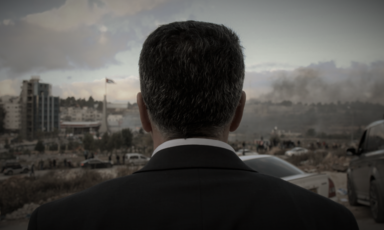 View of the back of a man's head in front of the Ramallah cityscape  