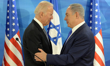 Joe Biden and Benjamin Netanyahu embrace in front of US and Israeli flags