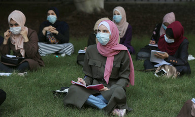 Women wearing masks sit outdoors 
