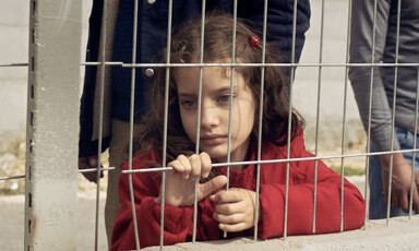 A girl stands behind a metal grill