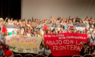 Activists gather on a stage and hold banners