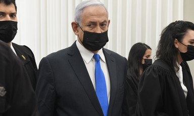 Netanyahu is seen from the waist up while wearing a mask inside a courtroom