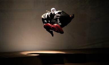 A man in traditional Palestinian black and white headgear flies through the air