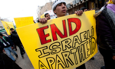 Youth carries sign reading End Israeli Apartheid while marching down street