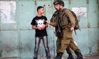 Two soldiers grab a boy's arm