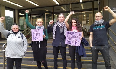 Five people raising fists and holding two signs