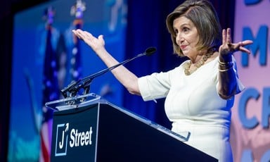 A woman stands at podium with arms outstreched