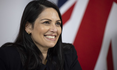 A woman smiles in front of a British flag