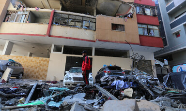 Man stands beside a badly damaged building 
