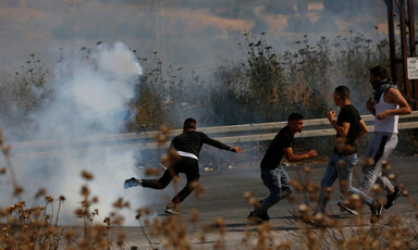 Men run away from cloud of tear gas smoke 