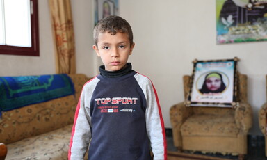 Boy stands in front of framed photograph 