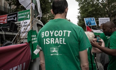 Man in crowd wears T-shirt reading Boycott Israel with icon of a shopping cart