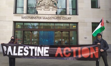 Two protesters hold a "Palestine Action" banner outside a court