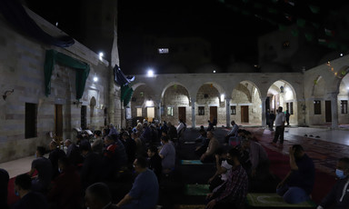Men pray in the dark in an outdoor mosque courtyard