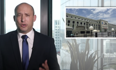 Man speaks on screen with photo of building inset