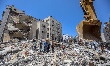 People walk over rubble of destroyed buildings 