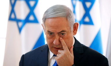 Benjamin Netanyahu touches a finger to his face