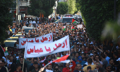 Large crowd of demonstrators holding two large banners, flags 