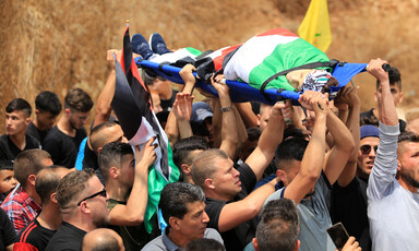 Men carry the body of a boy wrapped in a flag on a stretcher 