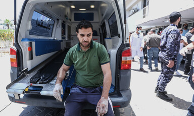 A man rests by the open back of an ambulance