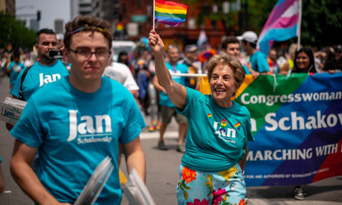 Woman waves rainbow flag as people march