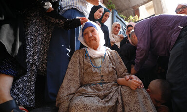 An older woman is surrounded by people some comforting one another