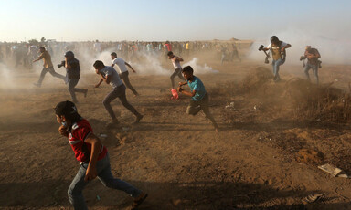 A cloud of white smoke surrounds people as they run 