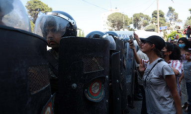 Protesters stand beside police in full riot gear 