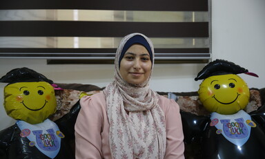 A woman poses with two balloon graduates