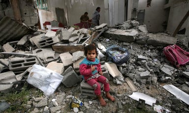 A young child sits in rubble