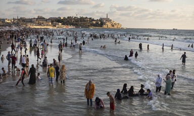 Women and children play on a beach in the sea