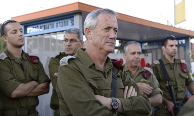 Several men in military uniforms stand with arms folded