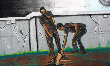 Mural depicts two men reaching out for a hand in a hole in the ground