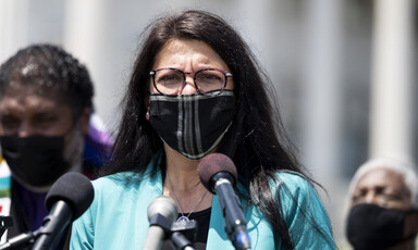 Woman at microphones with two people behind her