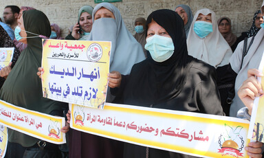 Women stand close together holding signs