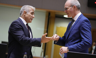 Two men in suits smile and gesture